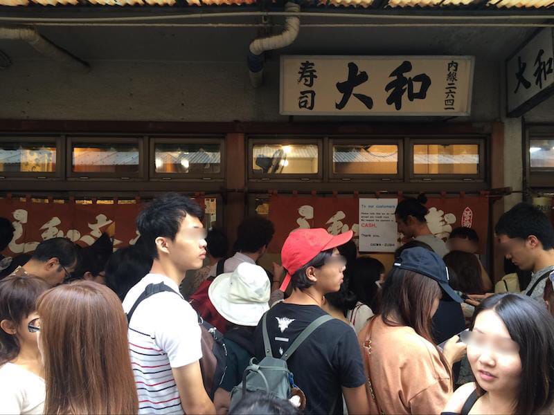 寿司屋の前に並ぶ訪日外国人